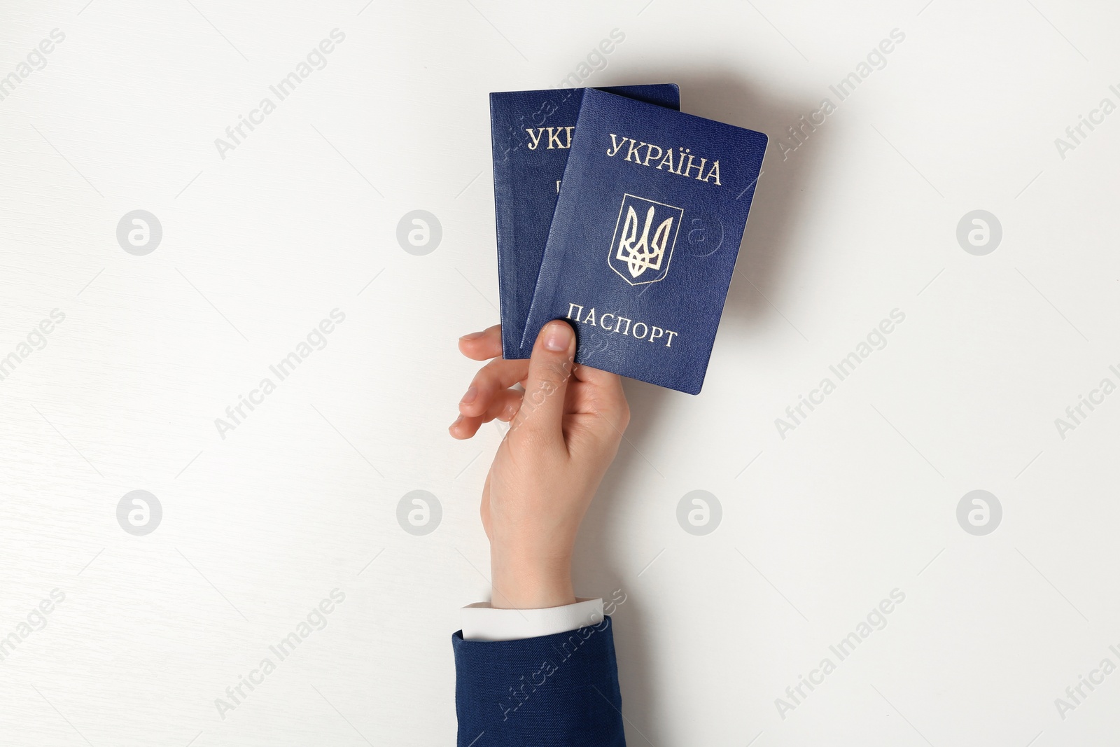 Photo of Woman holding Ukrainian internal passports on light background, top view