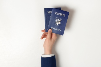 Photo of Woman holding Ukrainian internal passports on light background, top view