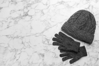 Photo of Stylish gloves and hat on white marble background, flat lay. Space for text