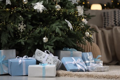 Photo of Many different gifts under Christmas tree on carpet indoors