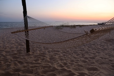 Photo of Empty hammock on beach at sunset. Time to relax