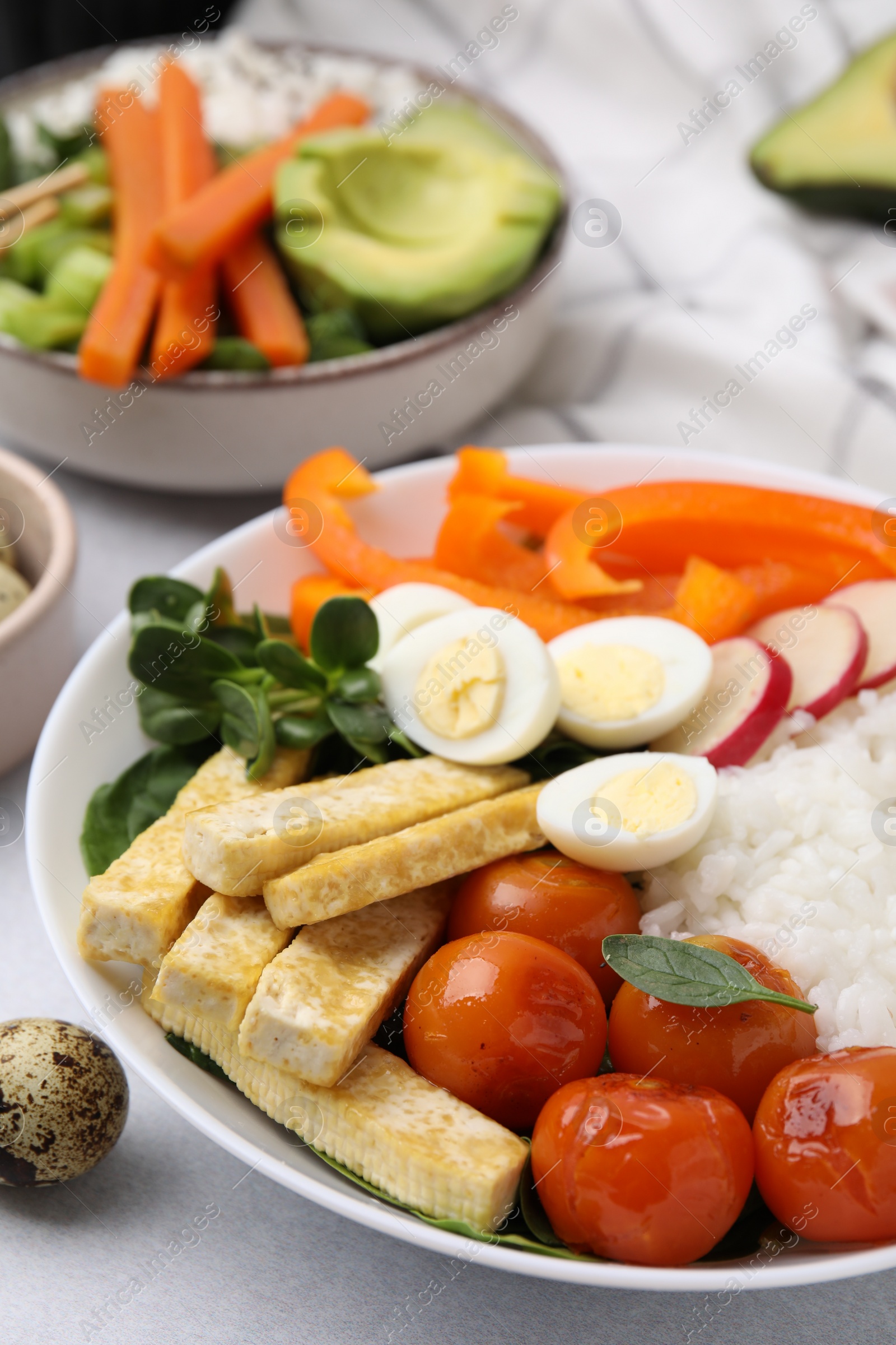 Photo of Delicious poke bowl with basil, vegetables, eggs and tofu on light grey table