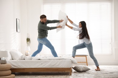 Happy young couple having fun pillow fight in bedroom