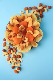 Photo of Mixed dried fruits and nuts on light blue background, flat lay