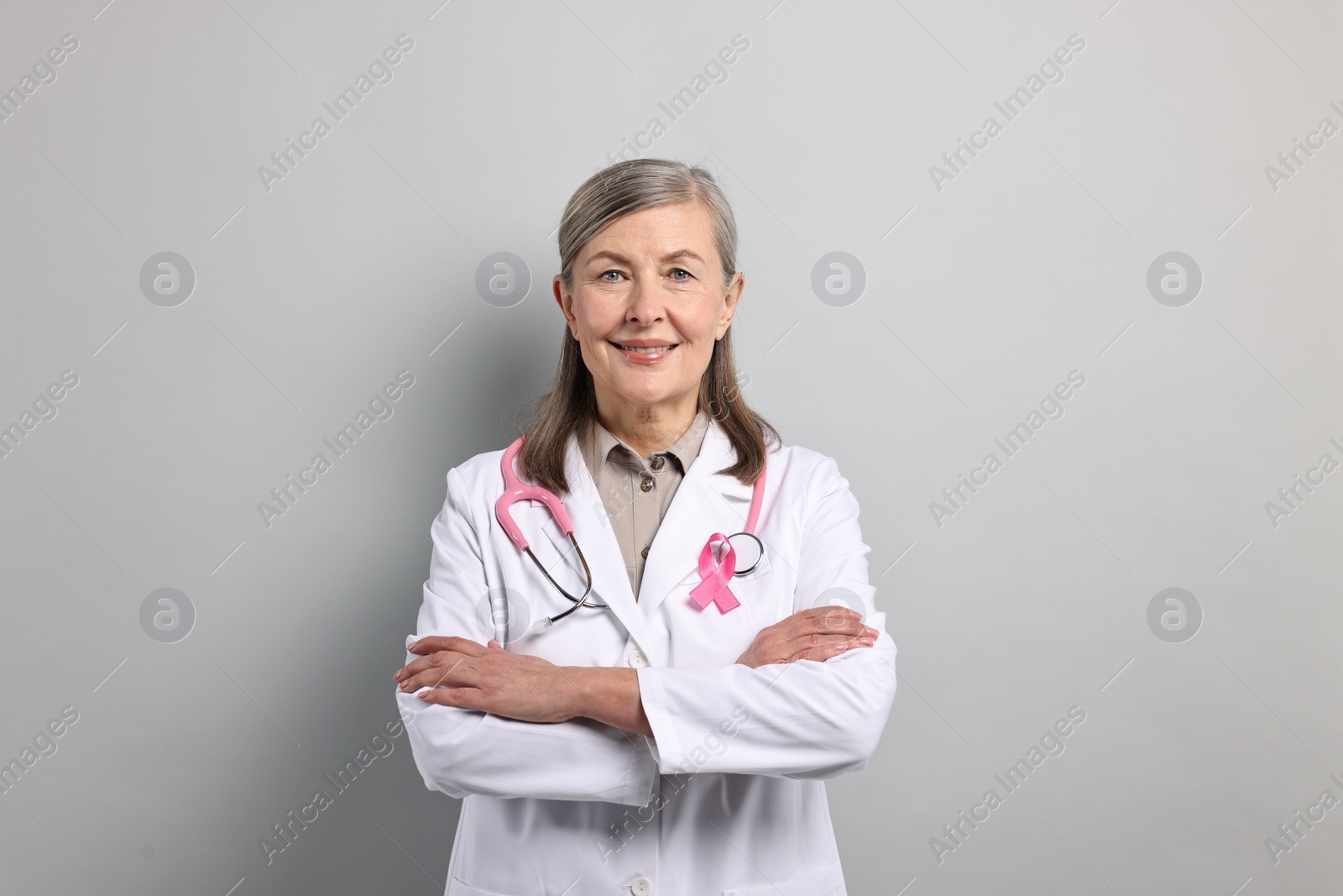 Photo of Mammologist with pink ribbon on gray background. Breast cancer awareness