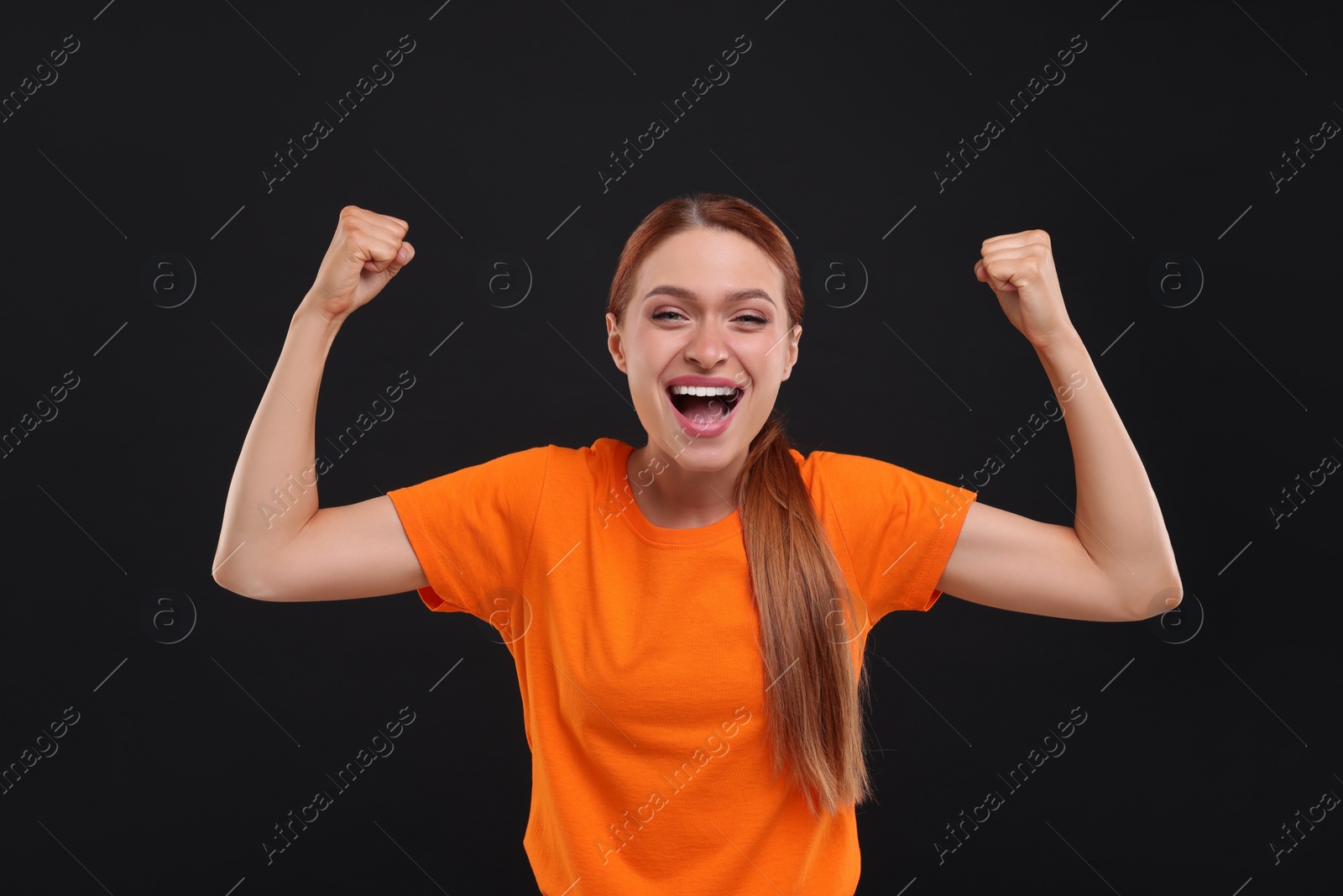 Photo of Excited sports fan in orange t-shirt on black background