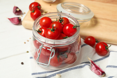 Photo of Pickling jar with fresh ripe cherry tomatoes and spices on white wooden table, closeup