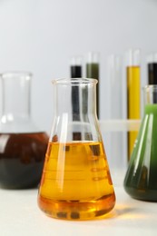 Photo of Laboratory glassware with different types of oil on white table, closeup
