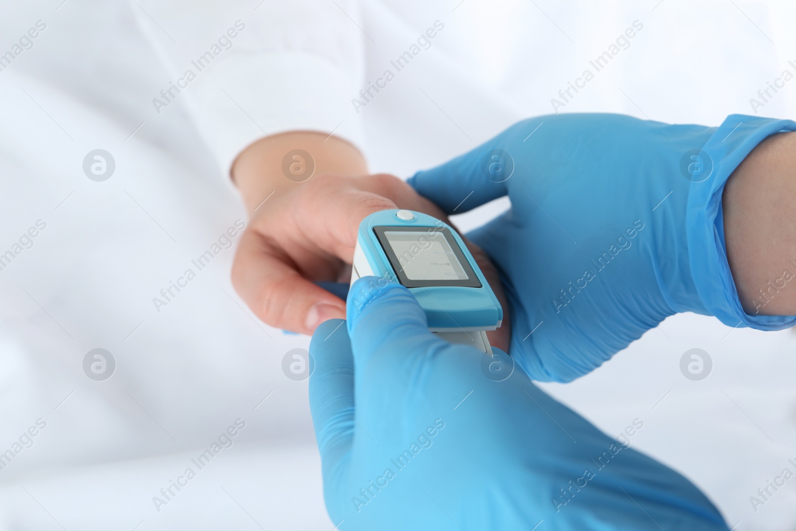 Photo of Doctor examining patient with modern fingertip pulse oximeter in bed, closeup