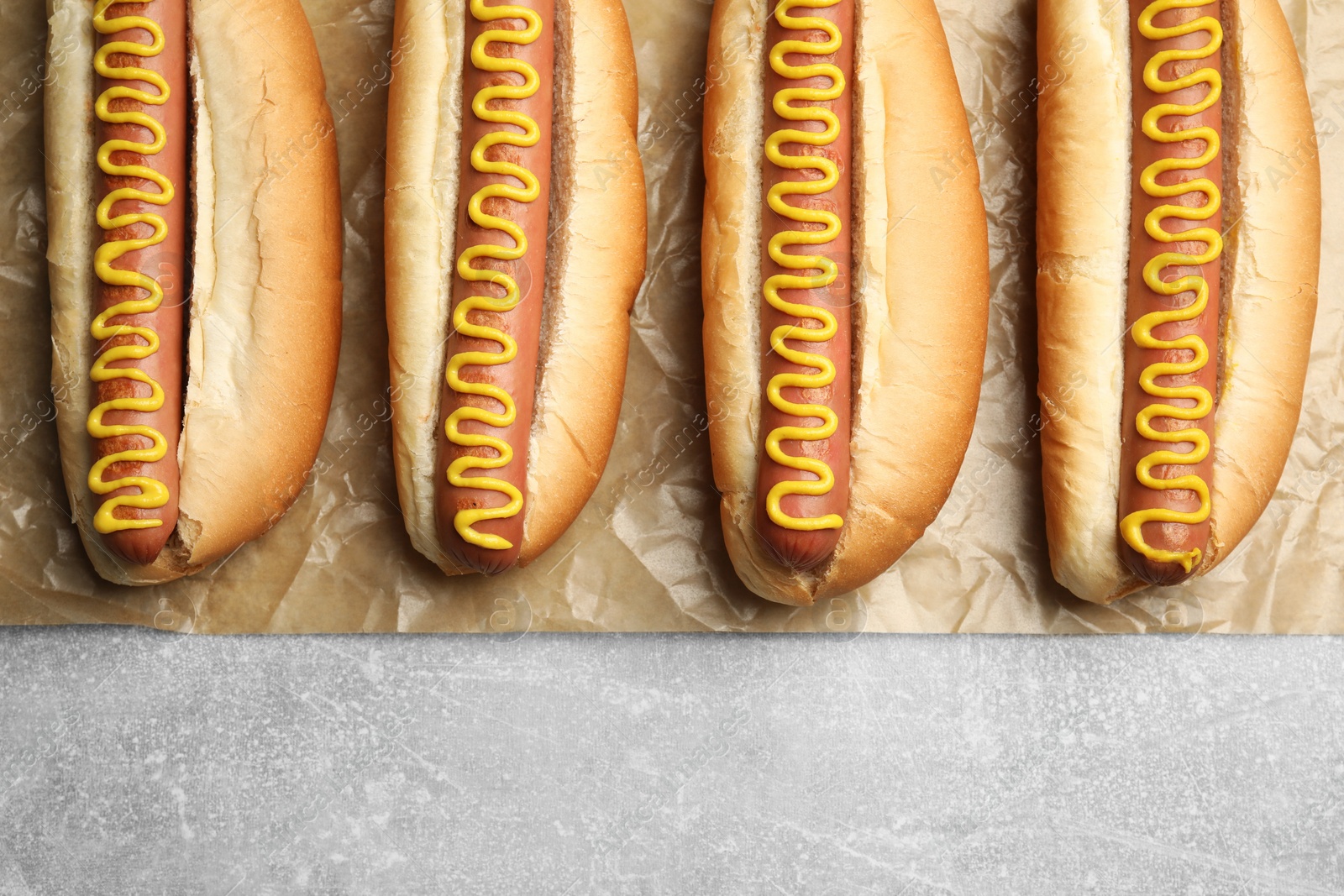 Photo of Fresh delicious hot dogs with mustard on light grey table, top view