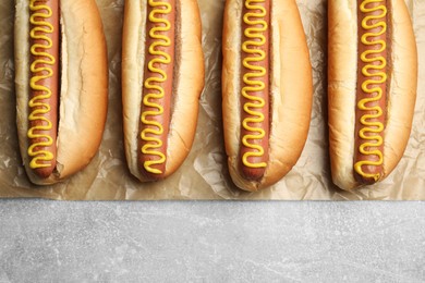 Photo of Fresh delicious hot dogs with mustard on light grey table, top view