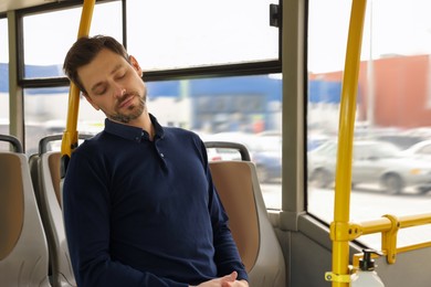 Tired man sleeping while sitting in public transport