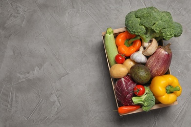 Photo of Crate with different fresh vegetables on grey background, top view. Space for text