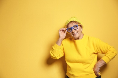 Photo of Portrait of elderly woman in hipster outfit on color background. Space for text