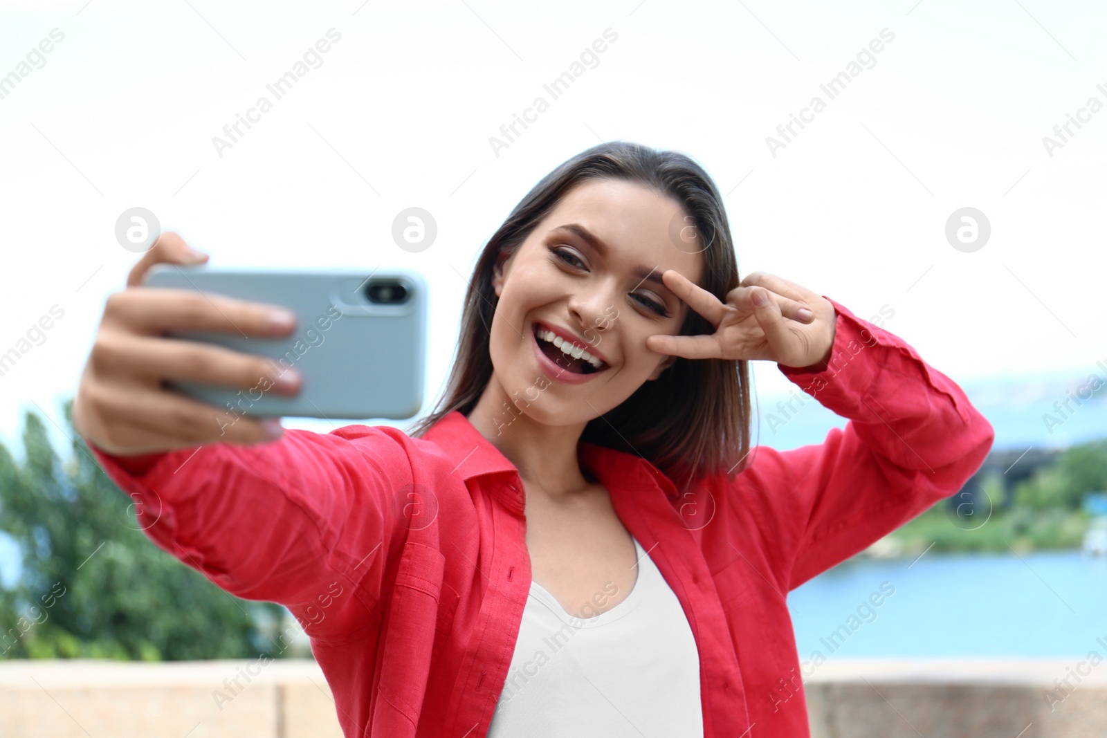 Photo of Happy young woman taking selfie on riverside