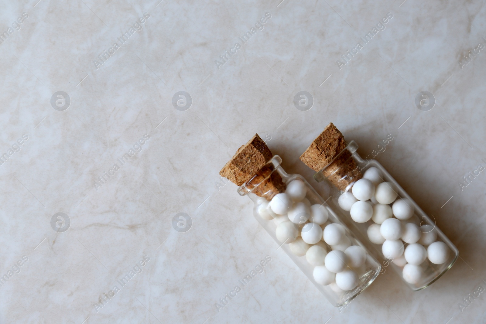 Photo of Bottles with homeopathic remedy on white table, flat lay. Space for text