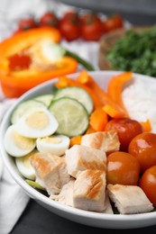 Photo of Delicious poke bowl with meat, rice, eggs and vegetables on black wooden table, closeup