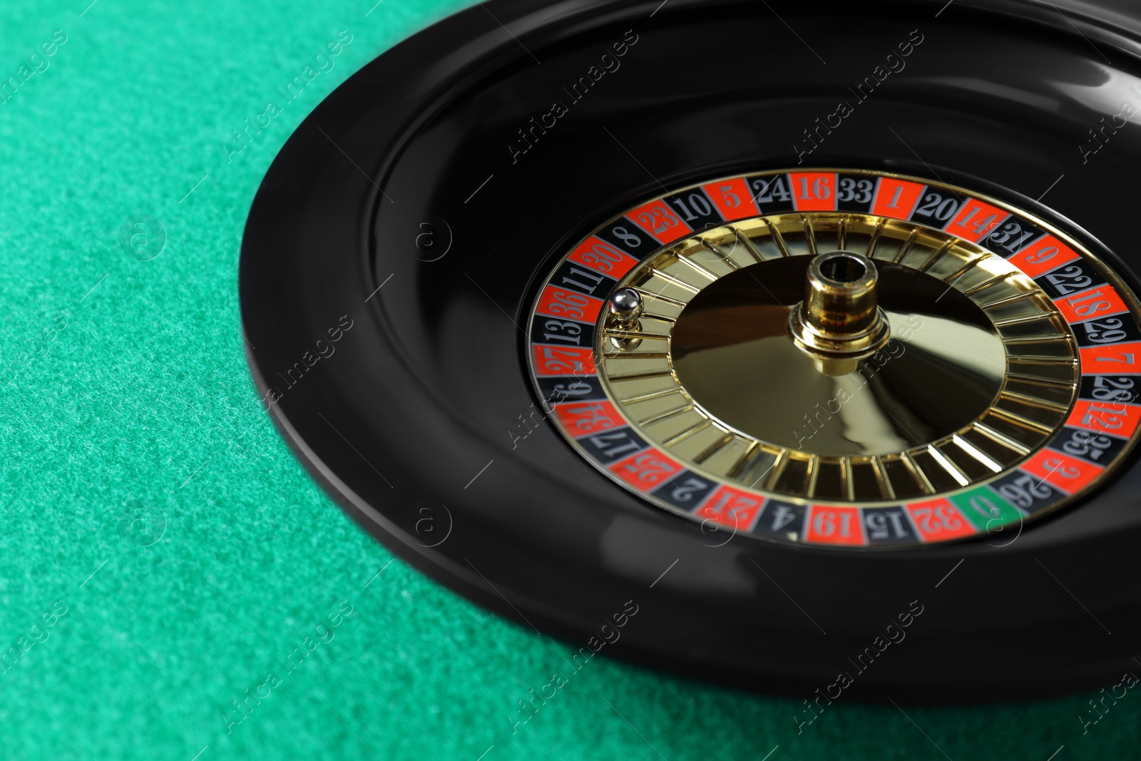 Photo of Roulette wheel with ball on green table, closeup. Casino game