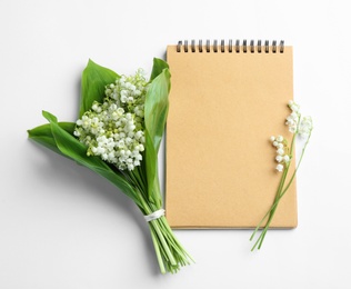 Notebook and lily of the valley bouquet on white background, flat lay. Space for text