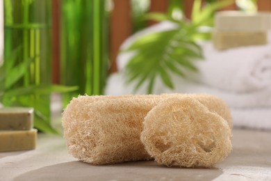 Photo of Natural loofah sponges on grey textured table