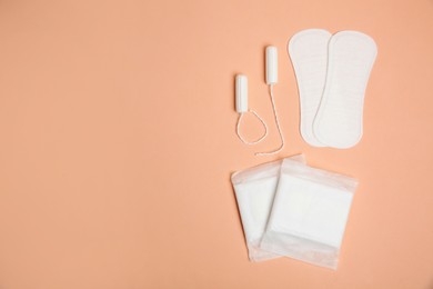 Photo of Menstrual pads, tampons and pantyliners on pale orange background, space for text