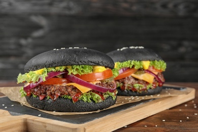 Photo of Board with black burgers on table. Space for text