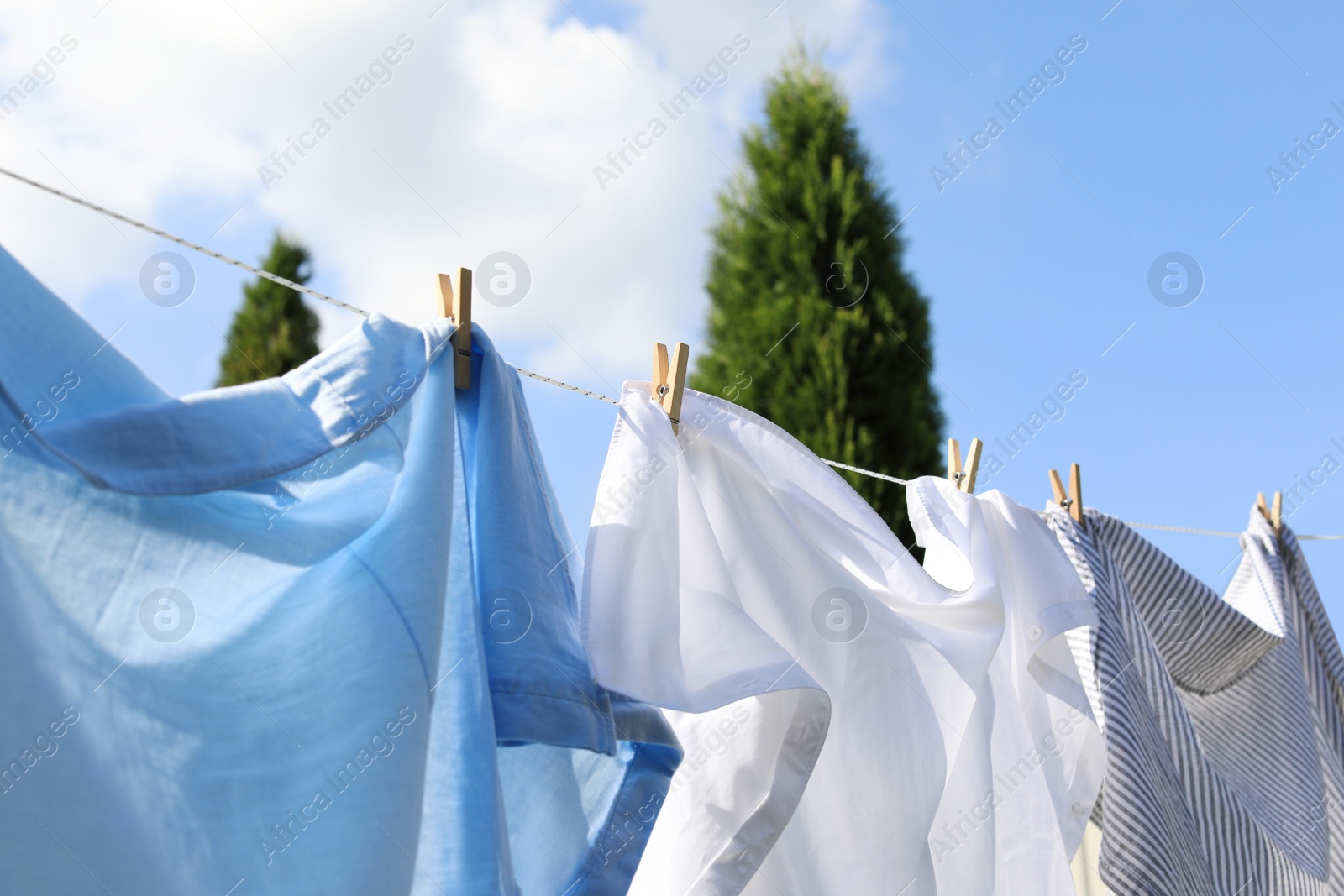 Photo of Clean clothes hanging on washing line outdoors, closeup. Drying laundry