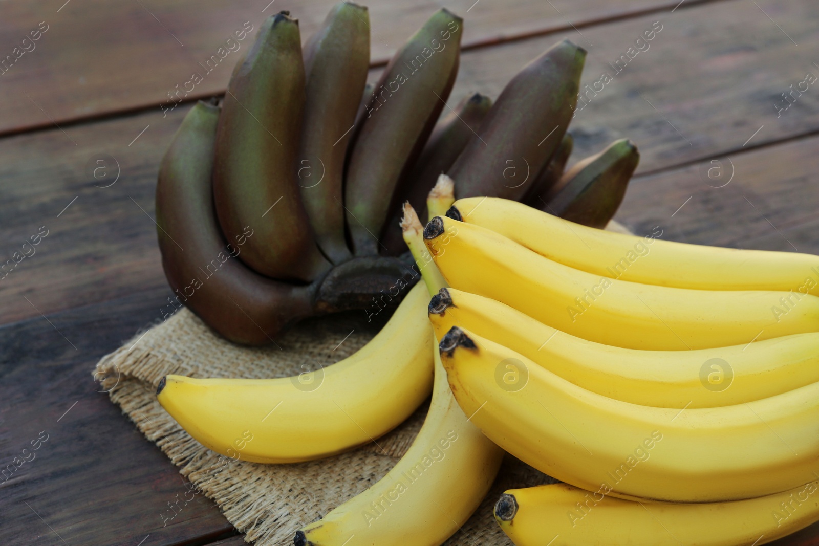 Photo of Tasty purple and yellow bananas on wooden table, closeup