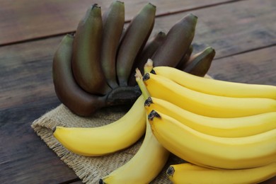 Tasty purple and yellow bananas on wooden table, closeup