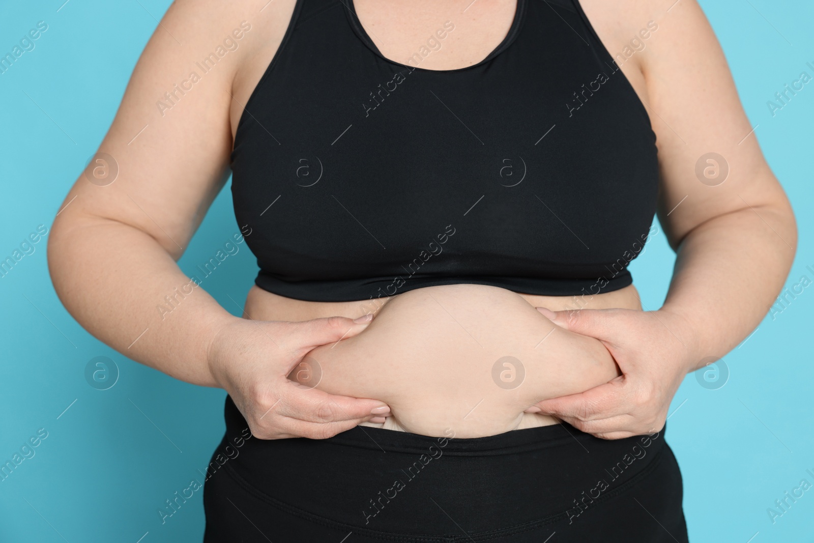 Photo of Obese woman on light blue background, closeup. Weight loss surgery