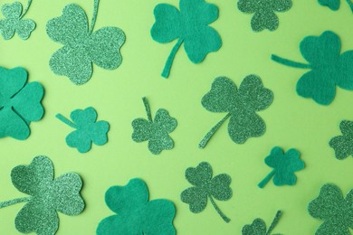 Photo of St. Patrick's day. Decorative clover leaves on green background, flat lay