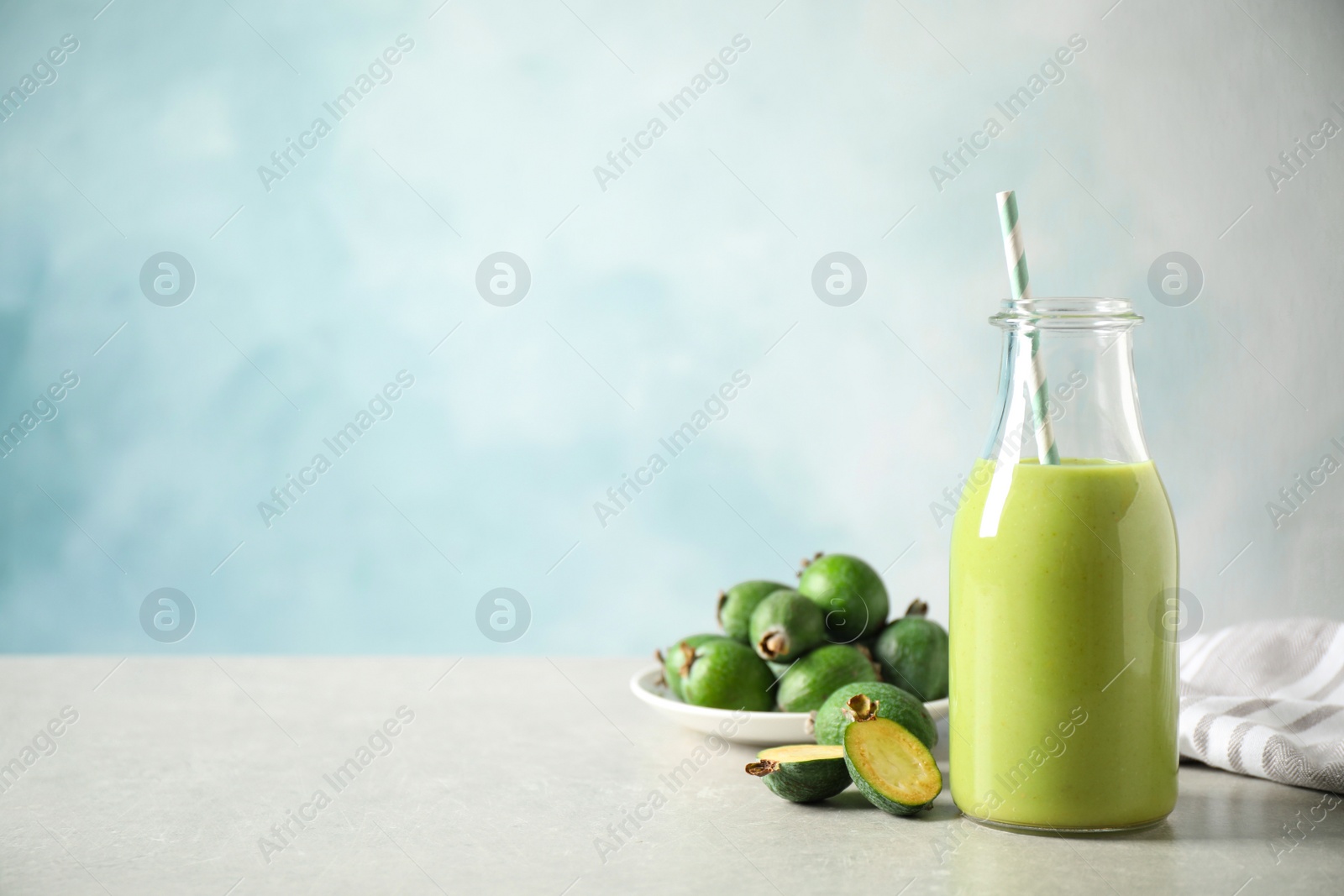 Photo of Fresh feijoa smoothie and fresh fruits on grey table, space for text