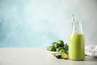 Fresh feijoa smoothie and fresh fruits on grey table, space for text