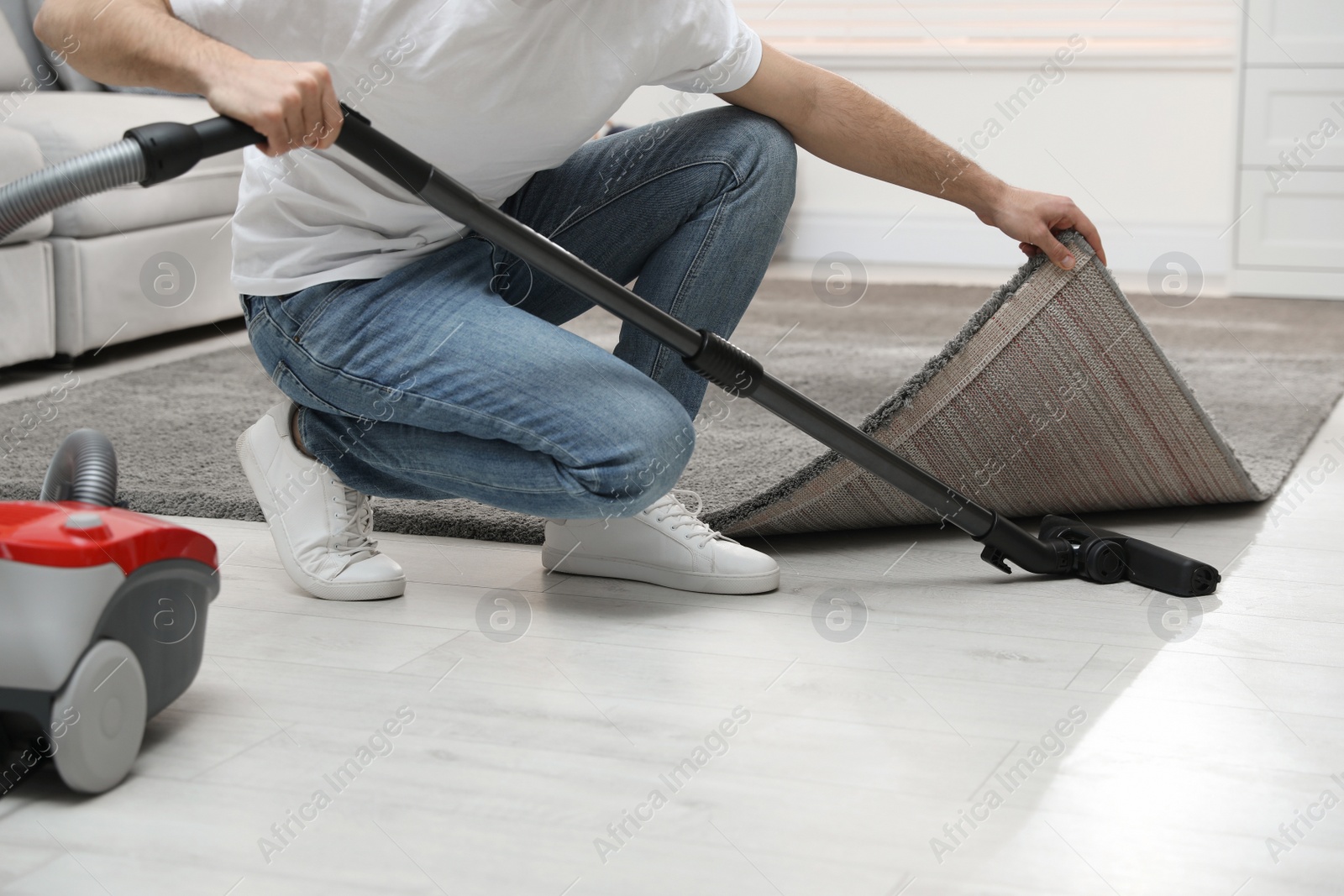 Photo of Young man using vacuum cleaner at home, closeup