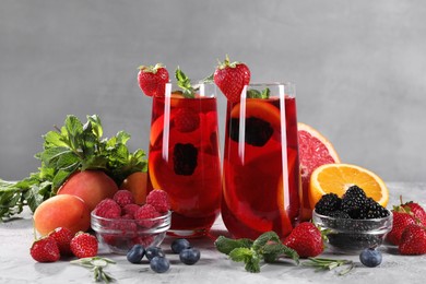Photo of Delicious refreshing sangria with fresh fruits and berries on light grey table