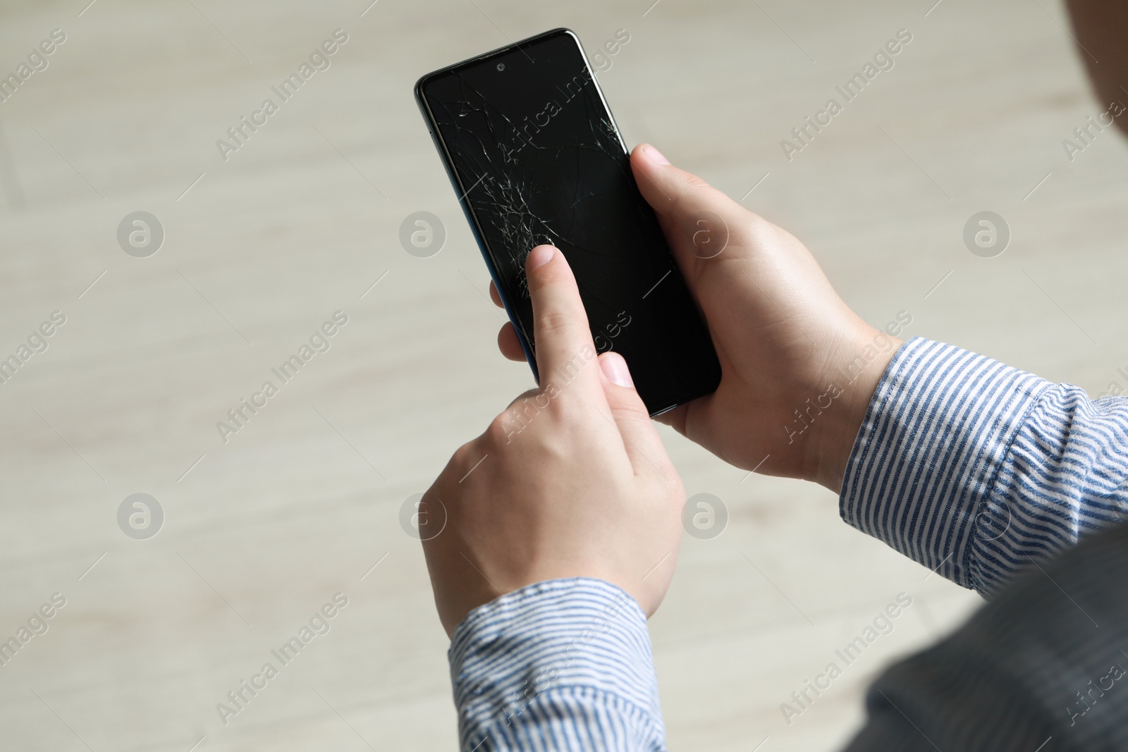 Photo of Man holding damaged smartphone indoors, closeup. Device repairing