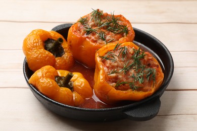 Photo of Tasty stuffed peppers in pan on light wooden table, closeup