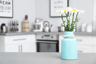 Photo of Vase with flowers and blurred view of kitchen interior on background