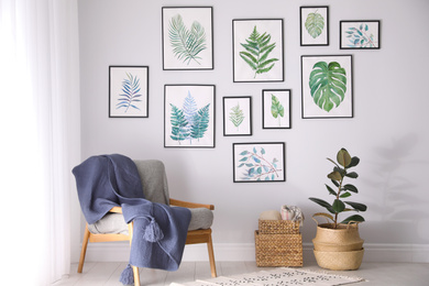 Beautiful paintings of tropical leaves on white wall in living room interior