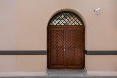 Photo of Entrance of building with brown wooden door and CCTV camera