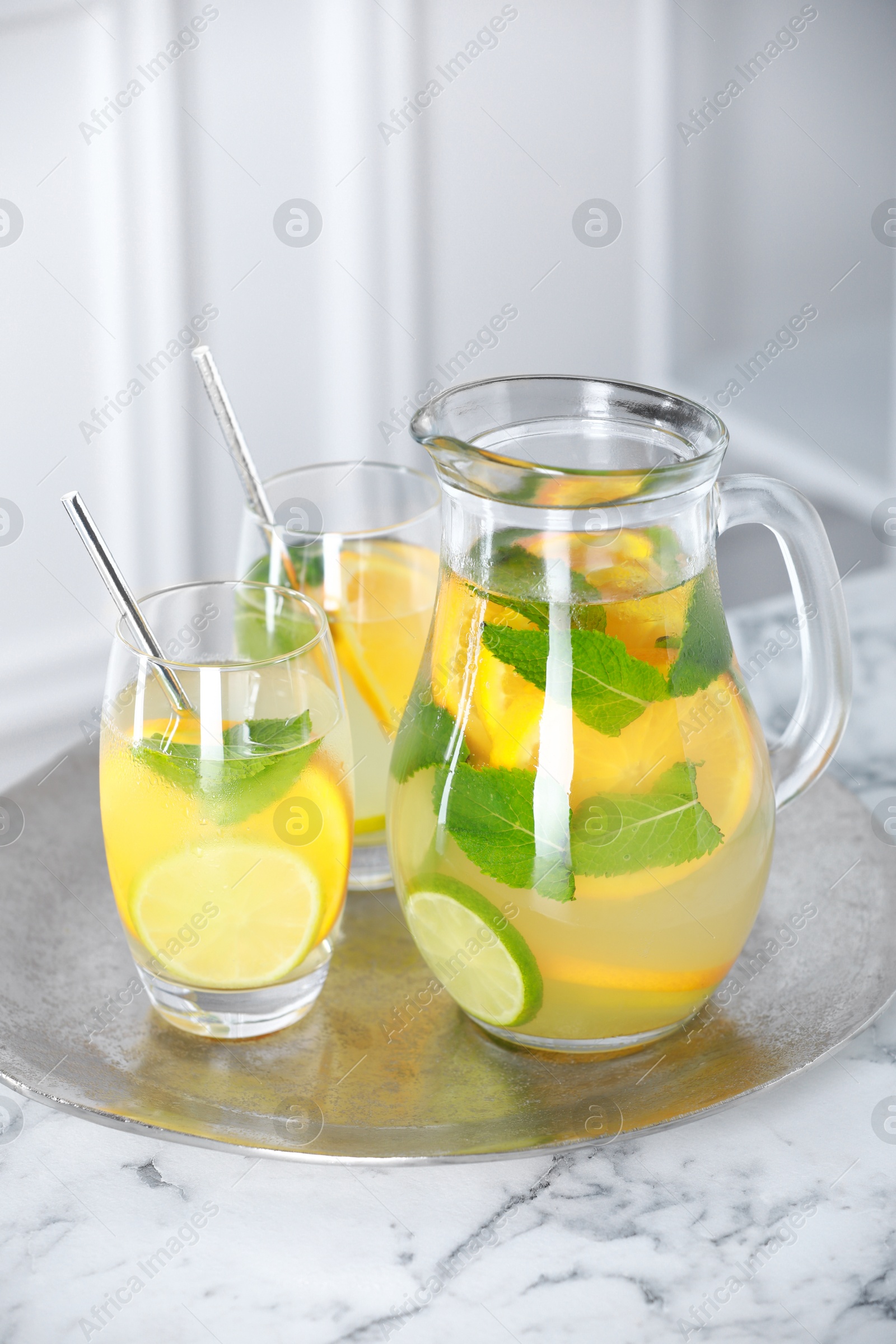 Photo of Freshly made lemonade with mint in jug and glasses on white marble table