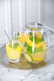 Photo of Freshly made lemonade with mint in jug and glasses on white marble table