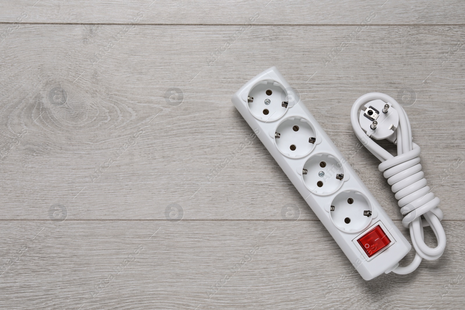 Photo of Power strip on wooden floor, top view. Space for text