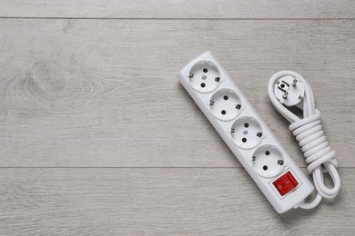 Photo of Power strip on wooden floor, top view. Space for text