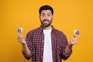 Photo of Man holding condoms on yellow background. Safe sex