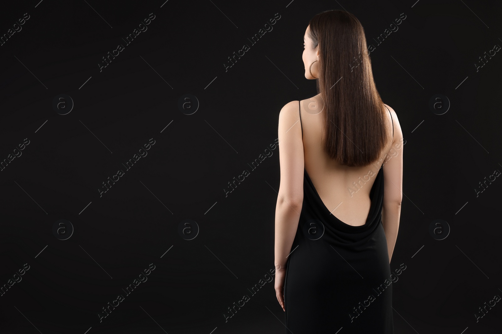 Photo of Woman in elegant dress on black background, back view. Space for text