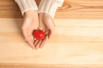 Woman holding decorative heart on wooden background, top view with space for text