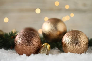Photo of Beautiful Christmas balls on snow against blurred festive lights. Space for text