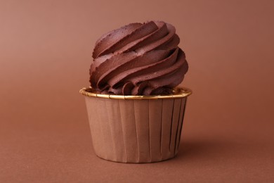 Delicious chocolate cupcake on brown background, closeup