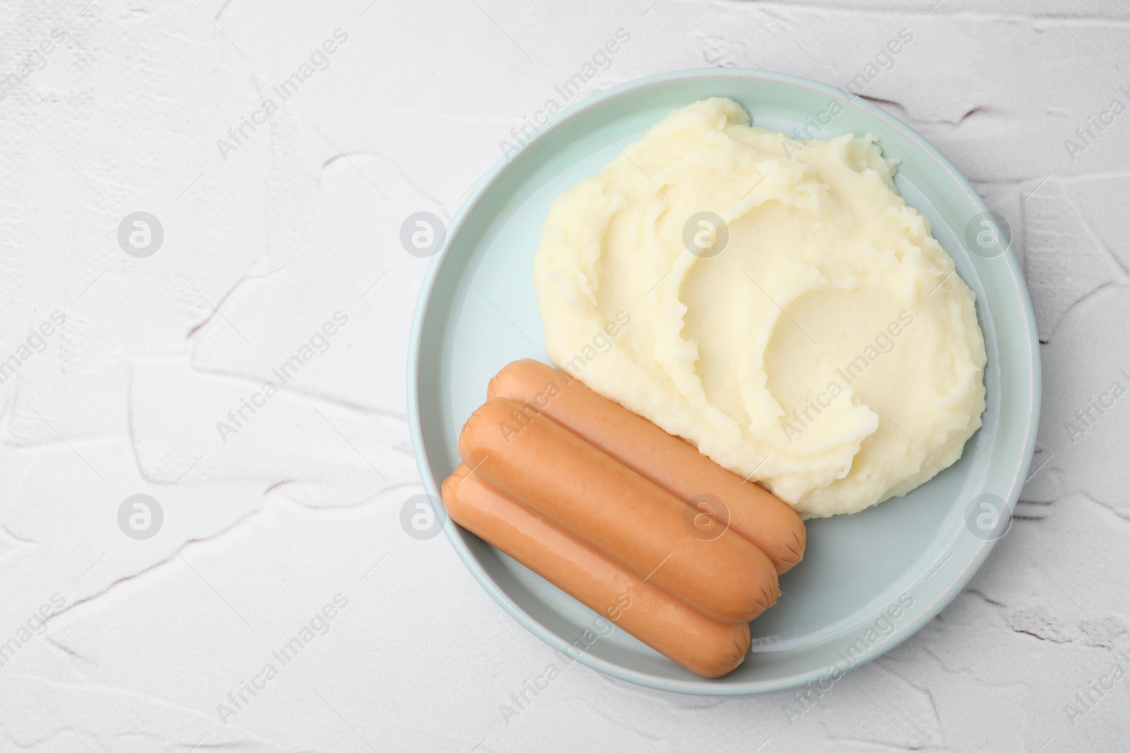 Photo of Delicious boiled sausages and mashed potato on white textured table, top view. Space for text